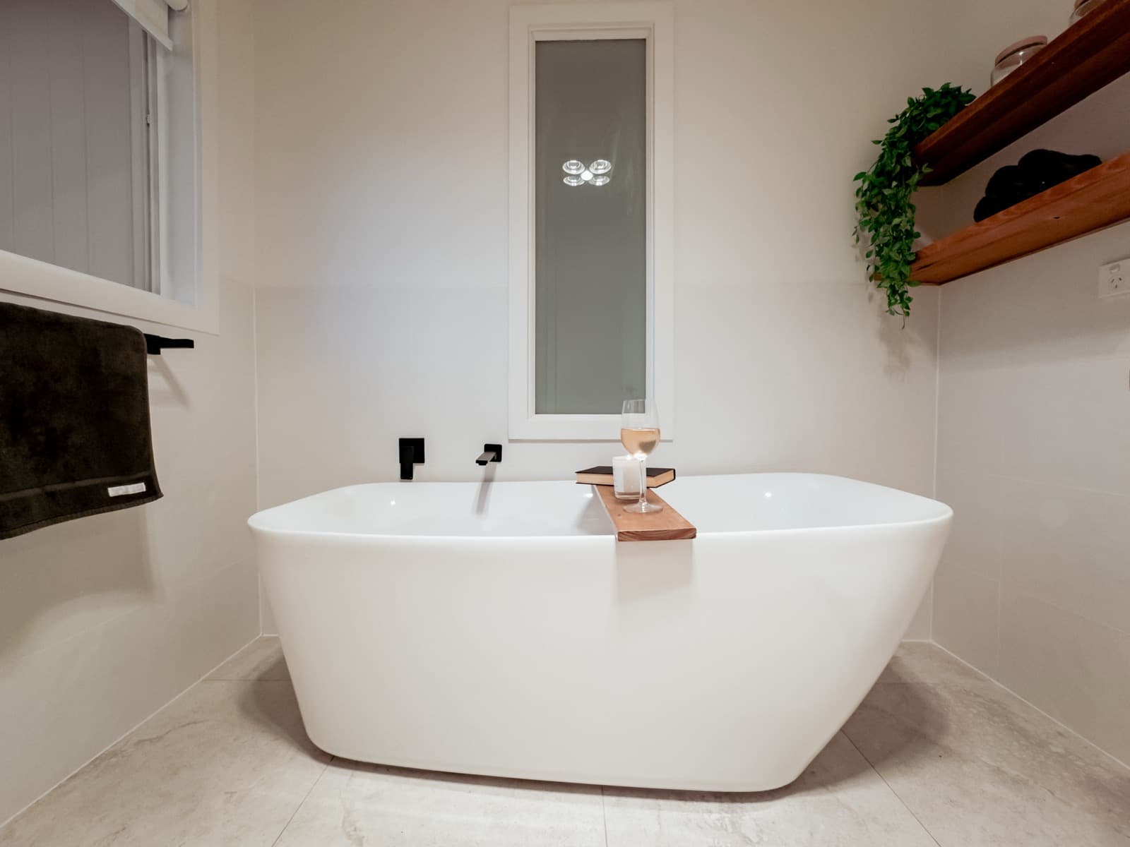 Freestanding bathtub with timber bath caddy and wine at Big Isle Retreat